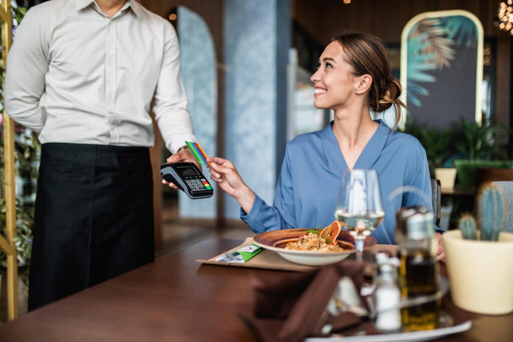 Woman in a restaurant paying for her meal using neobank, bunq card.